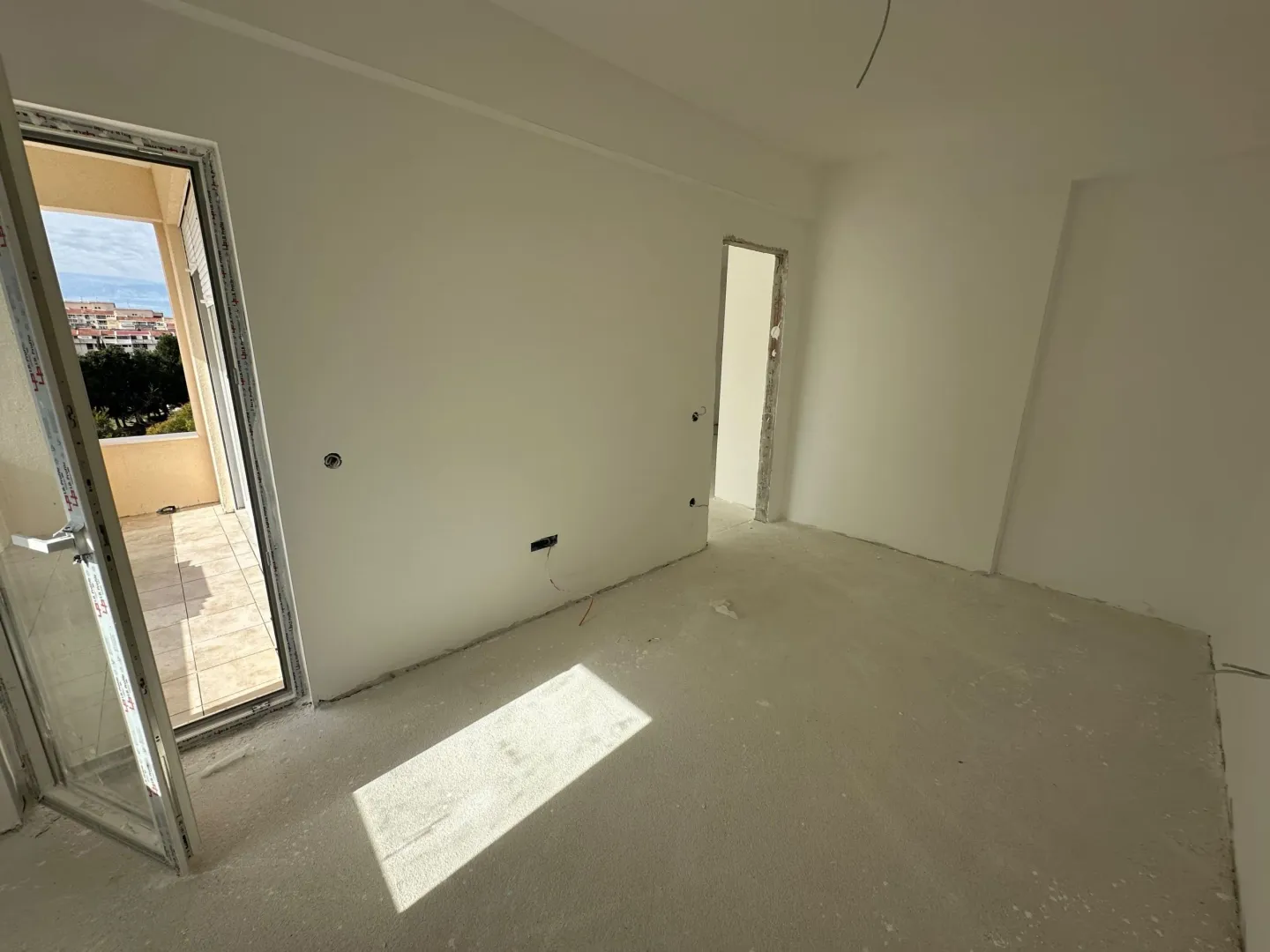 View of an unfinished room under construction with access to the terrace.