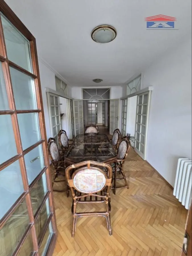 Spacious dining room with a wooden table and chairs, parquet flooring, and glass doors.