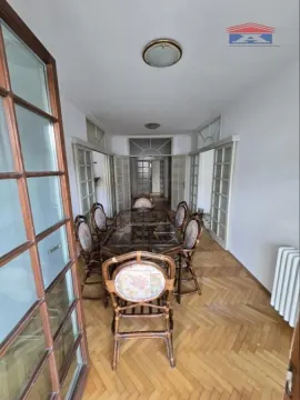 Spacious dining room with a wooden table and chairs, parquet flooring, and glass doors. - image 10