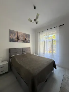 Spavaća soba sa bračnim krevetom, noćnim stočićima i prozorom sa bijelim zavjesama. - image 8