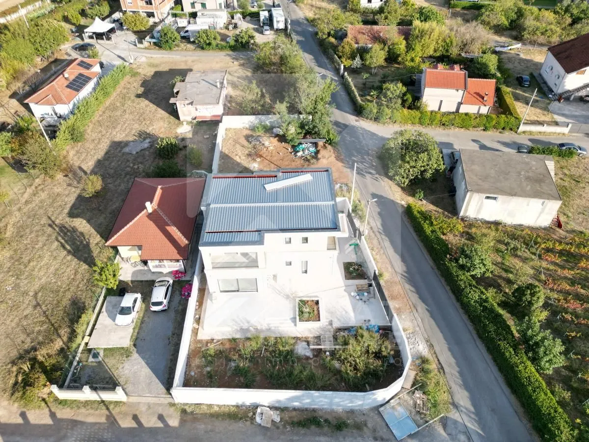 Pogled iz vazduha na kuću sa dvorištem i okolnim putem.