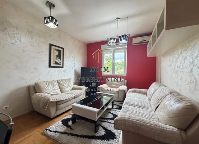 Dnevna soba sa garniturom za sedenje, stočićem i dekorativnim zidom.
