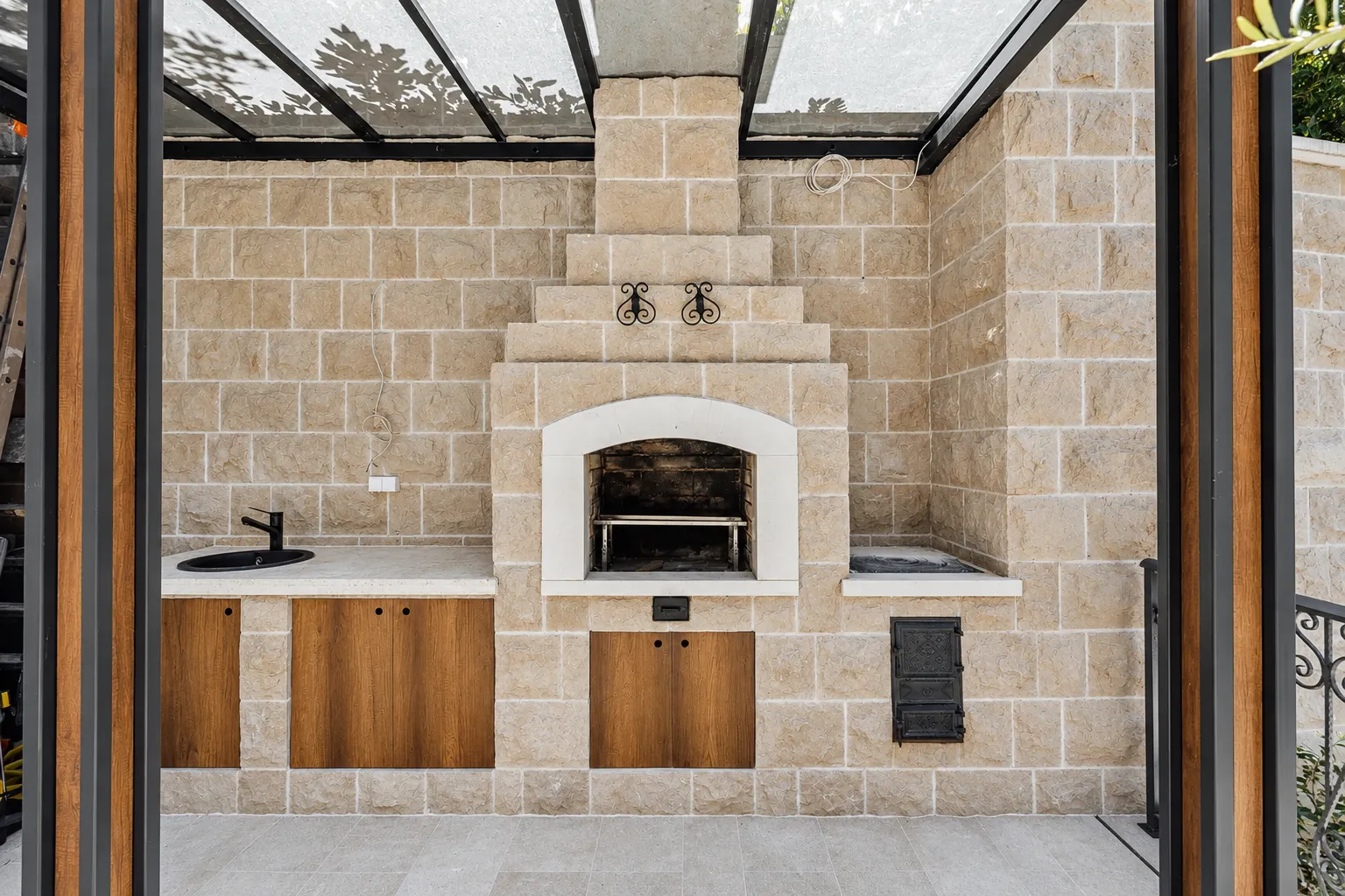 Covered outdoor area with a built-in barbecue, sink, and countertop.