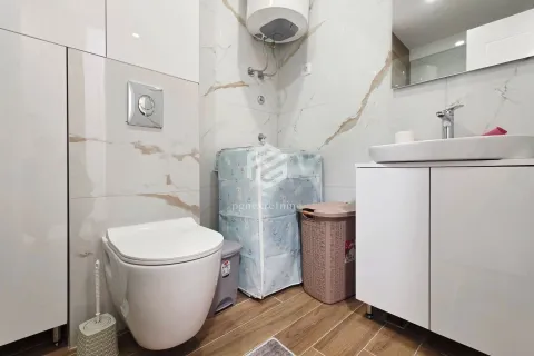 Smaller bathroom with a toilet, washbasin, water heater, and washing machine. - image 7