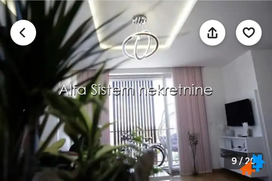 Pogled na dnevnu sobu sa modernim lusterom i izlazom na terasu.