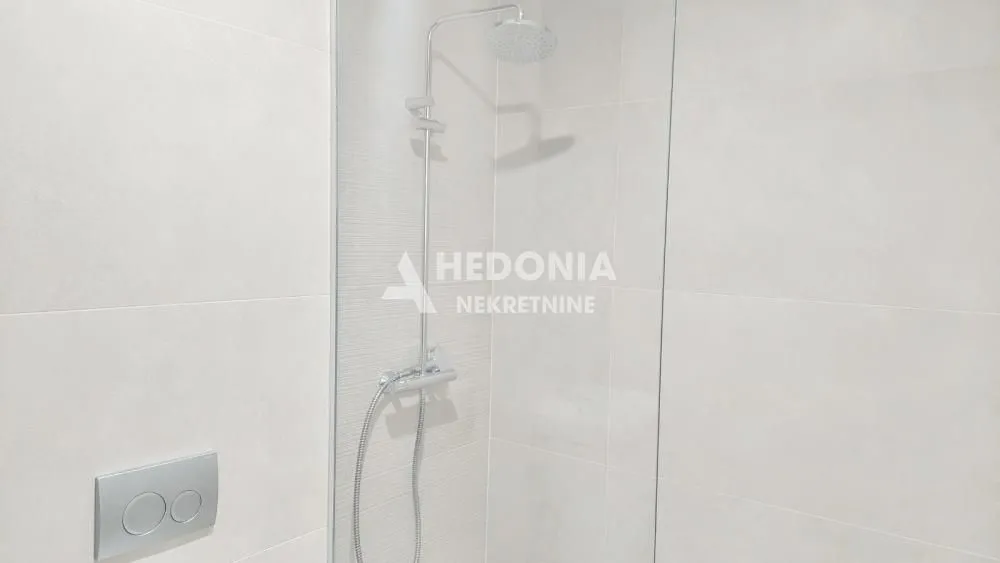 Moderna tuš kabina sa staklenom pregradom u svetlom kupatilu.
