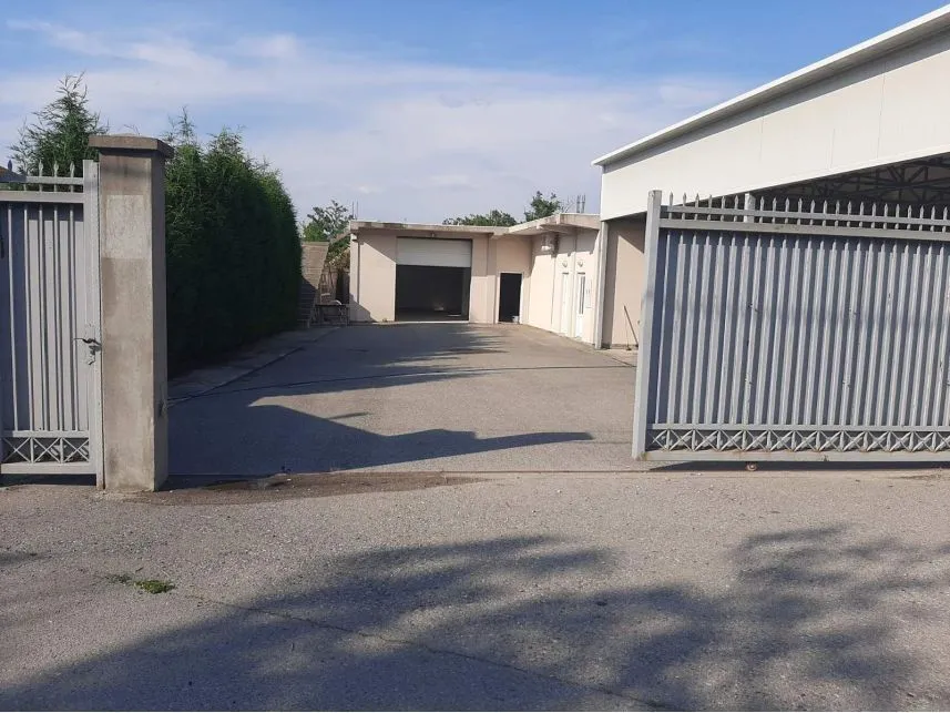 Driveway and entrance to the yard of a commercial building with a metal gate.