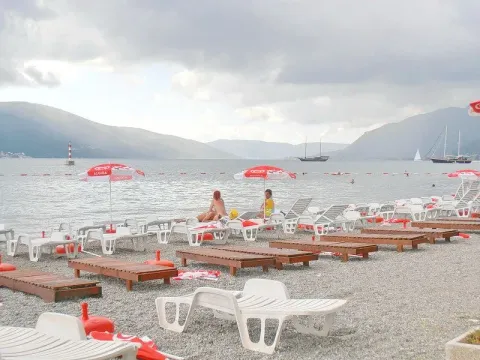 Pogled na šljunkovitu plažu sa ležaljkama i morem u pozadini. - image 11