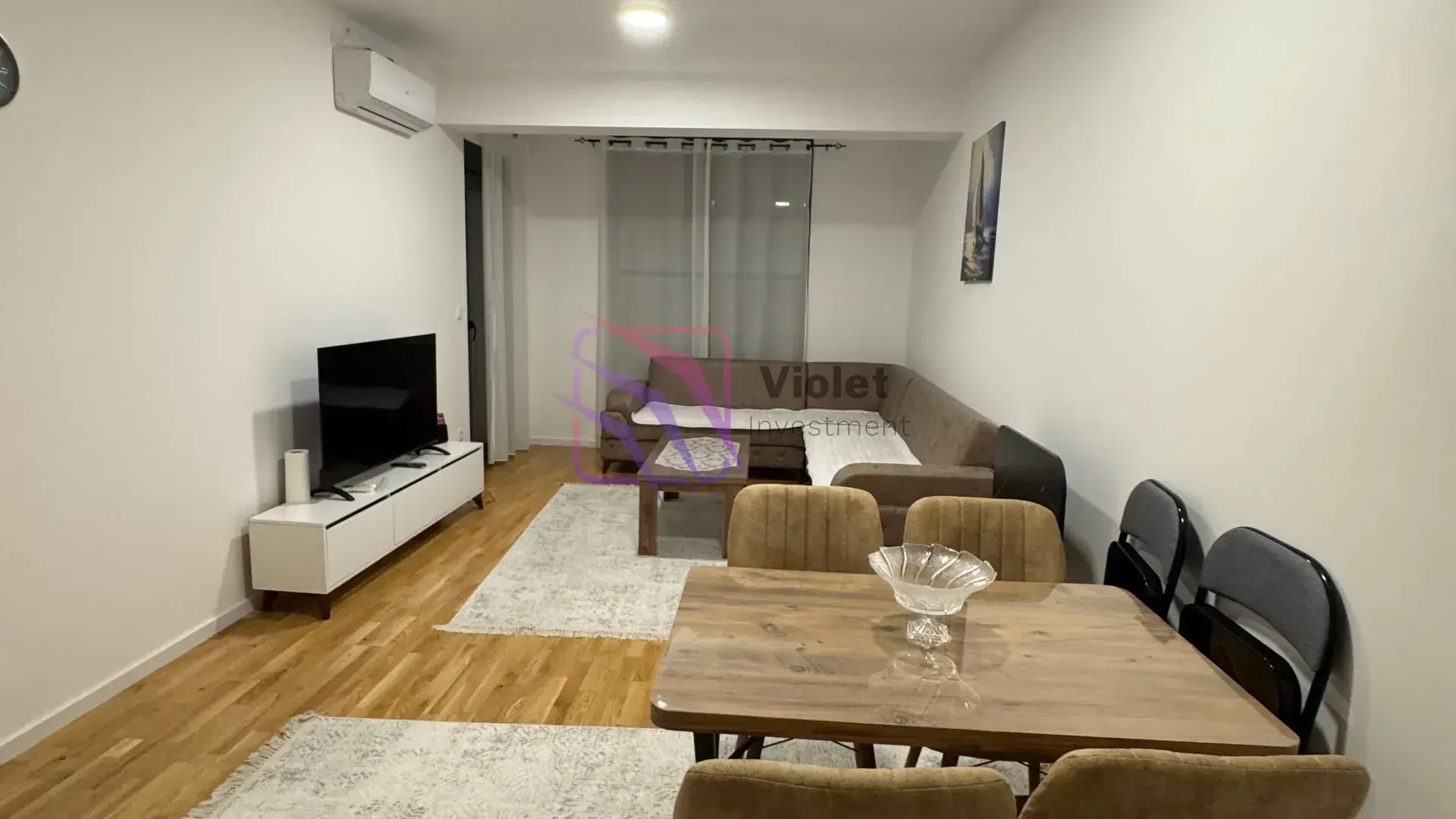 Living room with a sofa, TV, and dining table.