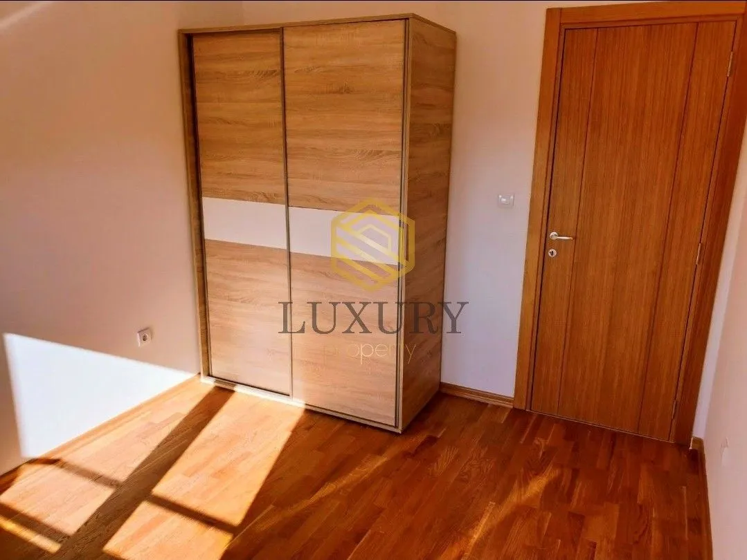 Small room with wooden wardrobe, parquet flooring and wooden door.
