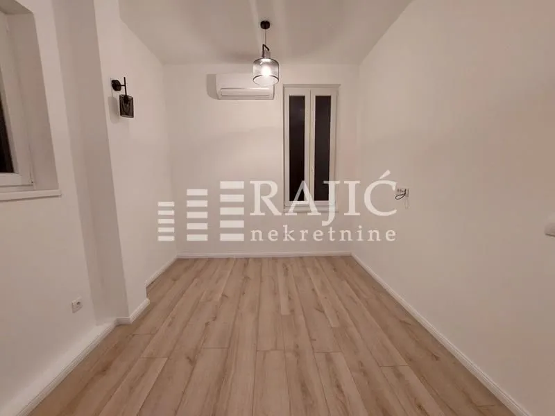 Empty room with laminate flooring and air conditioning.