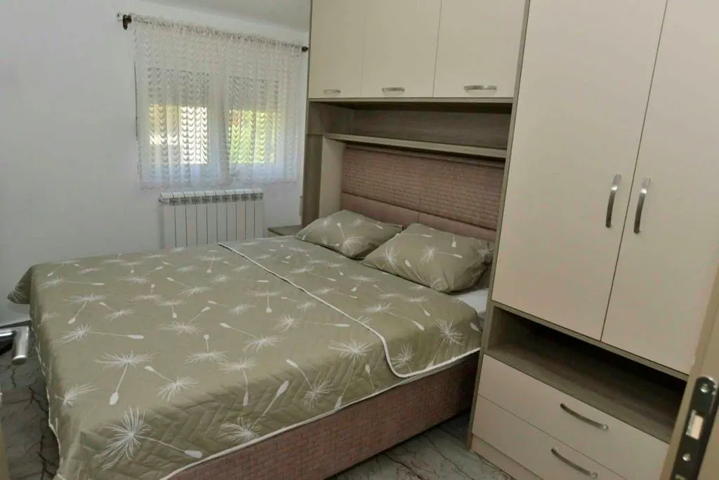 Namještena spavaća soba sa bračnim krevetom i ugradnim ormarom.