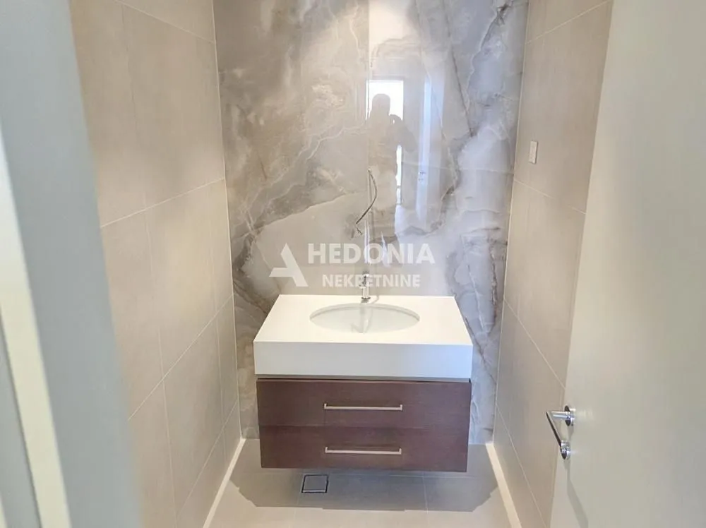 Moderno kupatilo sa umivaonikom i dekorativnim mermernim zidom.