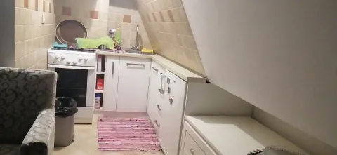 A small functional attic kitchen with white cabinets. - image 4