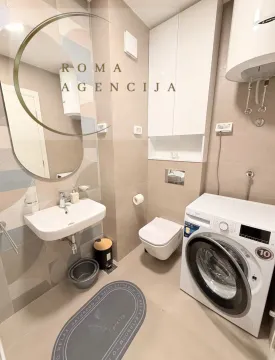 Modernly equipped bathroom with a washbasin, toilet, and washing machine. - image 8