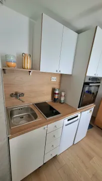 Small modern kitchen with white cabinets, a sink, a built-in hob, and an oven. - image 11