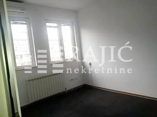 Empty room with two windows and dark flooring.