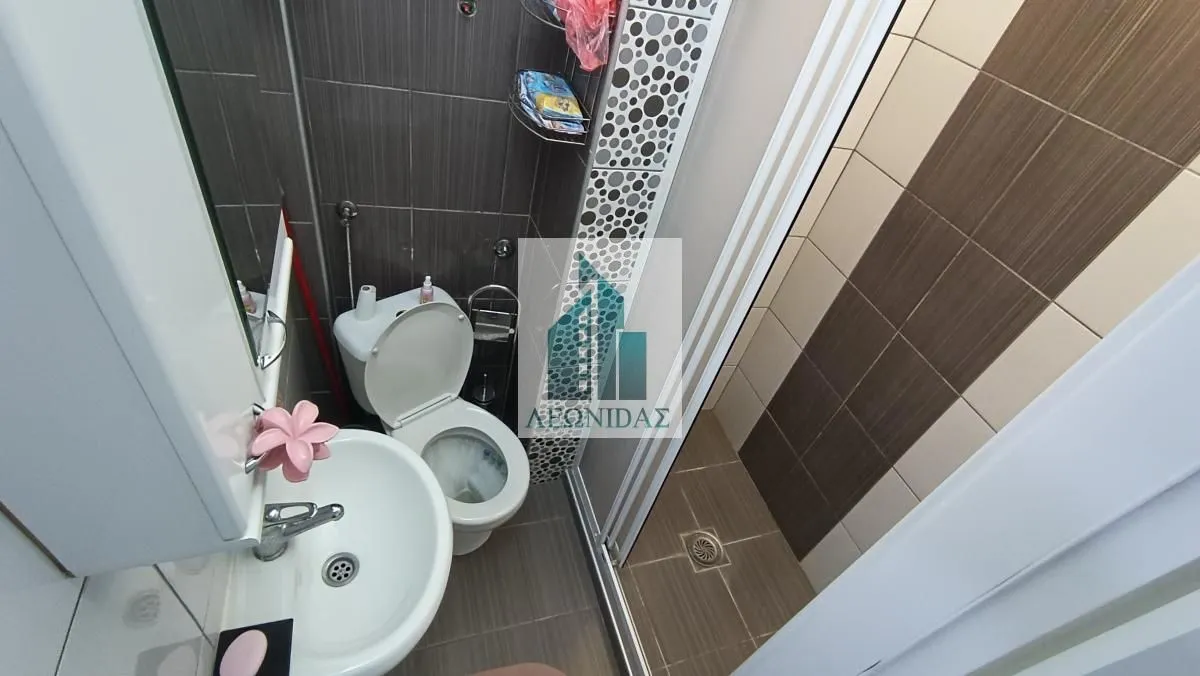Manje kupatilo sa umivaonikom, WC šoljom i tuš kabinom.