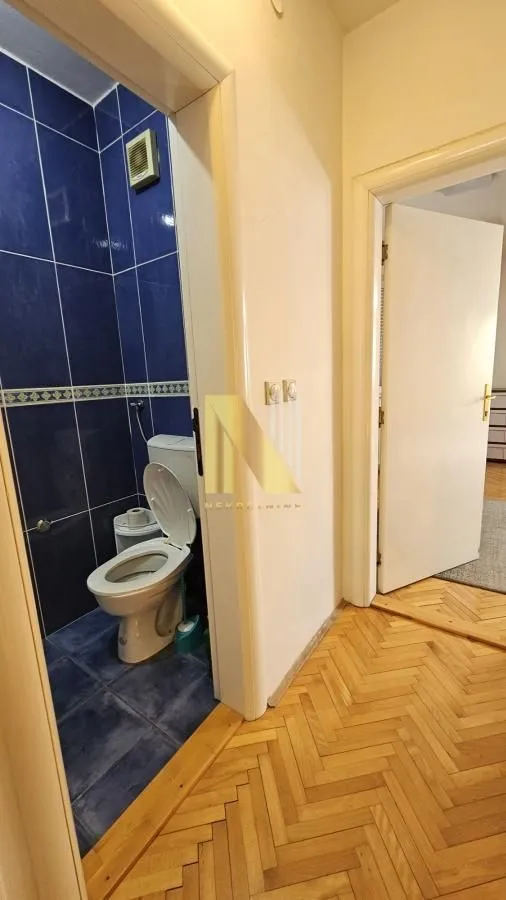 Hodnik sa pogledom na kupatilo obloženo plavim pločicama.