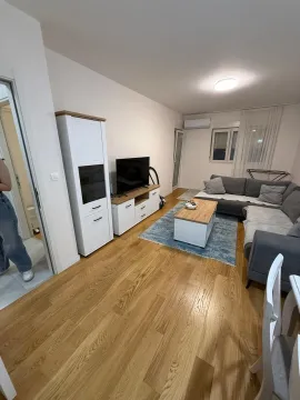 Furnished living room with a sofa, TV, and wooden flooring. - image 2