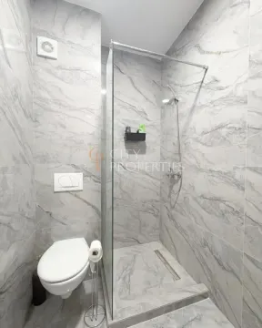 Modern bathroom with a walk-in shower and marble-style tiles. - image 13