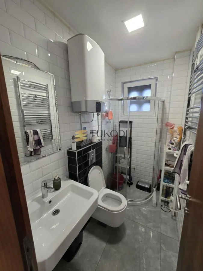 Bathroom with a shower cabin, washbasin, toilet, and water heater.