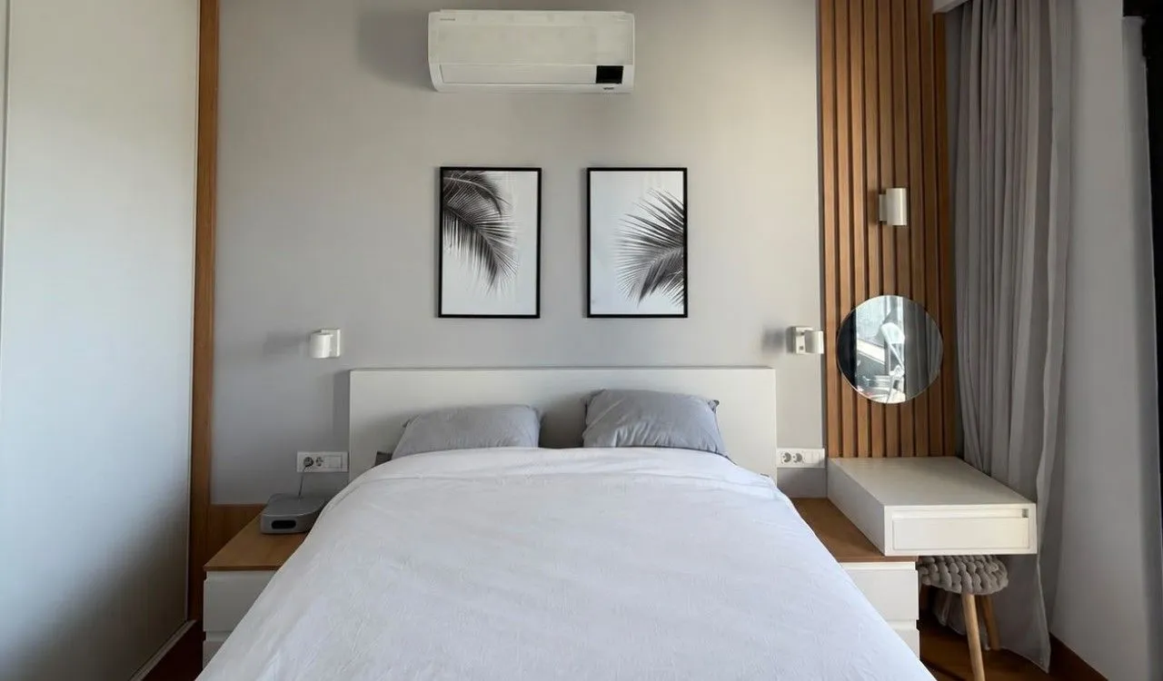 Moderna spavaća soba sa bračnim krevetom, klima-uređajem i drvenim zidnim panelima.