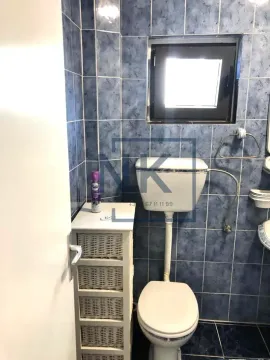 Small bathroom tiled in blue with a toilet and a window. - image 11