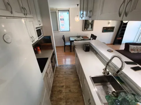 Compact kitchen with white cabinetry and a dining area in the background. - image 5