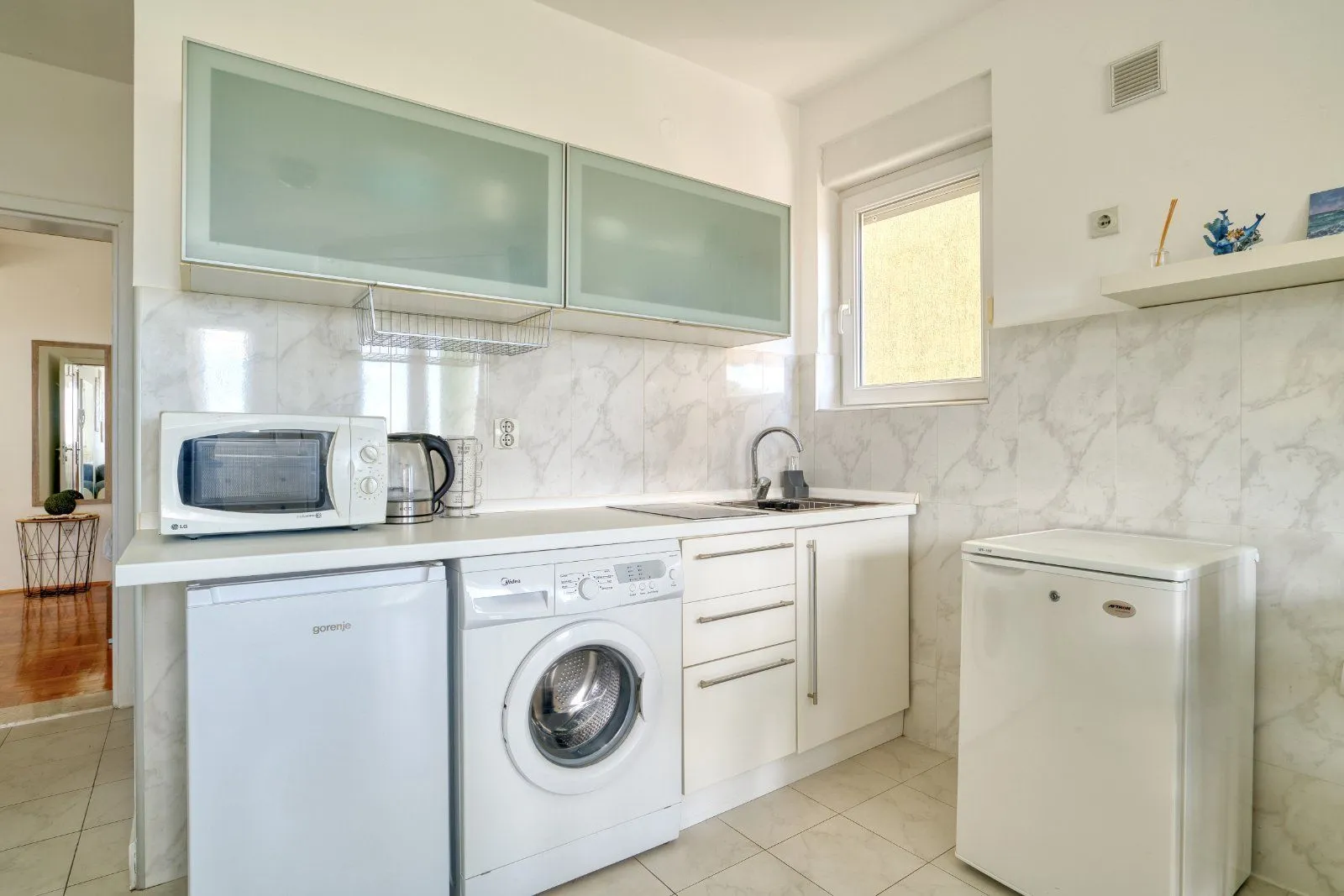 Small kitchen with white cabinets, a refrigerator, and a washing machine.