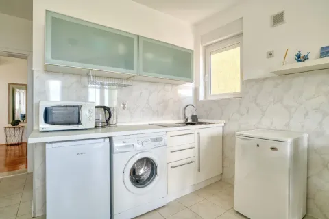 Small kitchen with white cabinets, a refrigerator, and a washing machine. - image 10