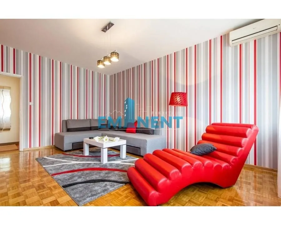Living room with a sofa, a red armchair and striped wallpaper on the wall.