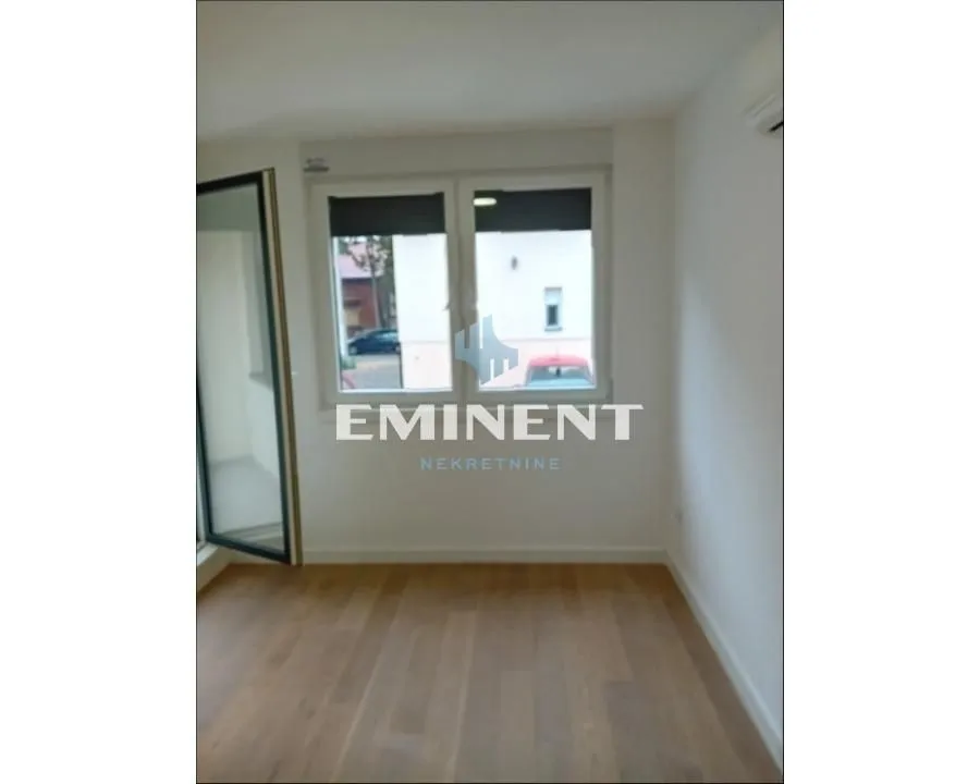 Empty room with parquet flooring and a window.