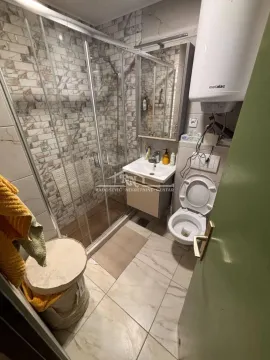 Bathroom with a shower cabin, washbasin, toilet, and water heater. - image 14