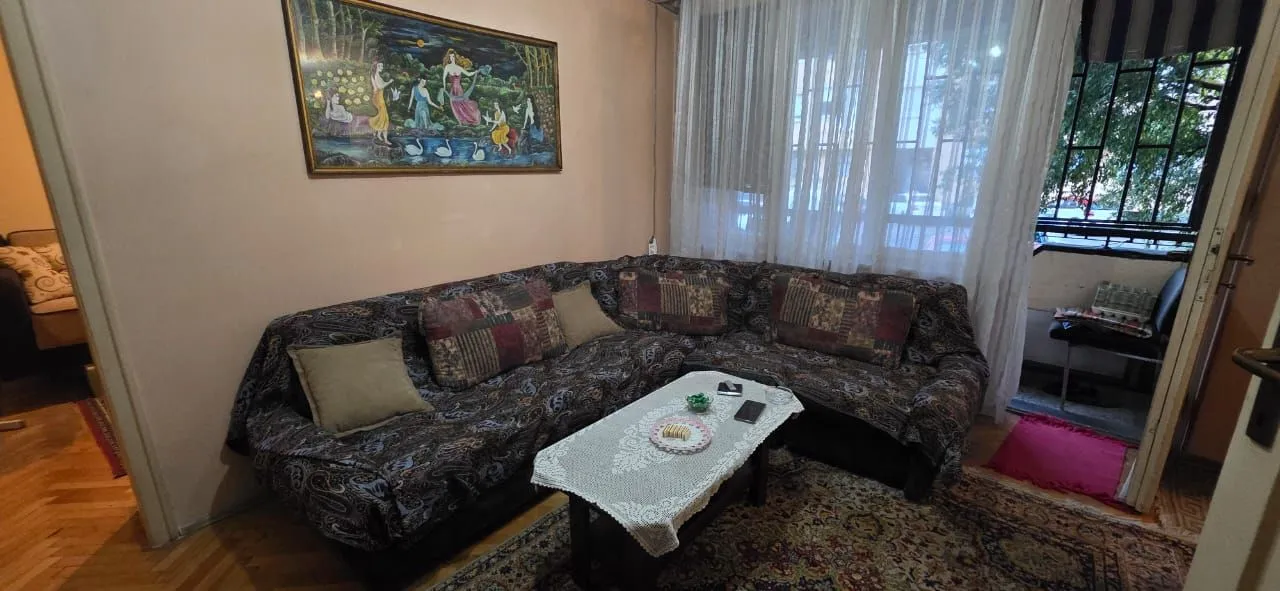 Dnevna soba sa garniturom za sjedenje, stočićem i umjetničkom slikom na zidu.