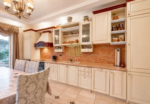 Spacious kitchen with light-colored cabinets and a dining table. - image 5