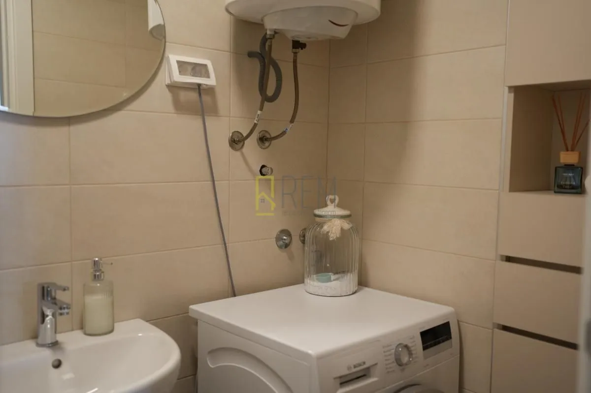 Small bathroom with a sink, washing machine, and wall-mounted water heater.