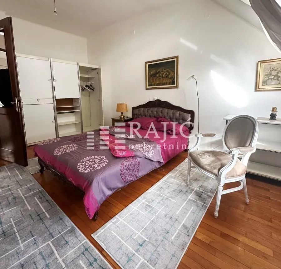 Furnished bedroom with a double bed, wardrobe, and armchair.