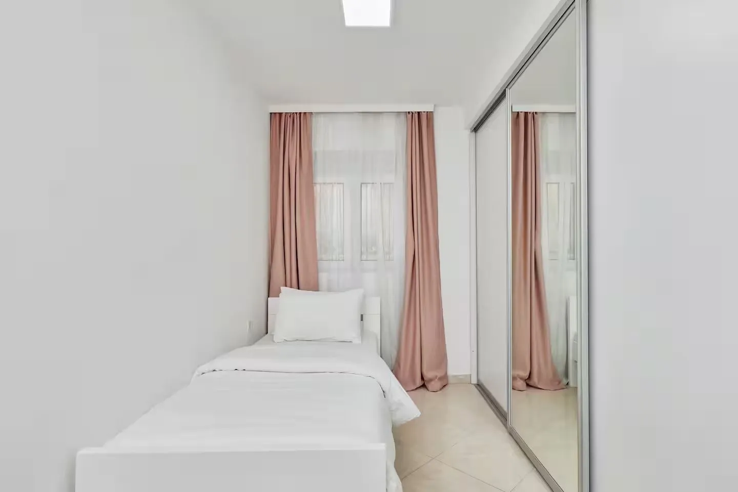 Small bedroom with a bed and a large built-in mirrored wardrobe.