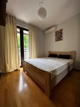 Namještena spavaća soba sa bračnim krevetom, drvenim podom i izlazom na balkon. - image 6