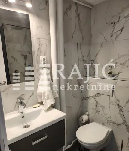 Smaller bathroom tiled with marble-patterned ceramic tiles.