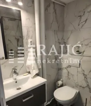 Smaller bathroom tiled with marble-patterned ceramic tiles. - image 6