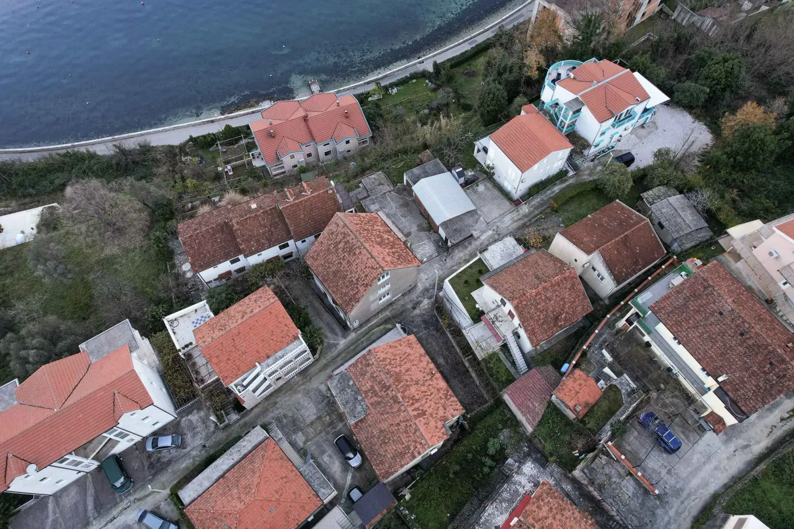 Pogled iz vazduha na naselje i okolne kuće blizu obale.