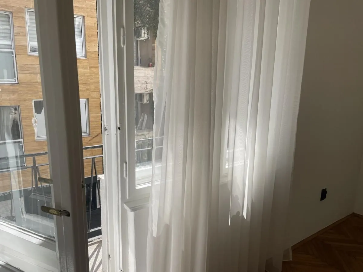 View through a window with white curtains towards the neighbouring building.