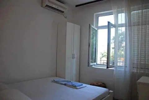 A bright bedroom featuring a double bed, a white wardrobe, and an open window. - image 7