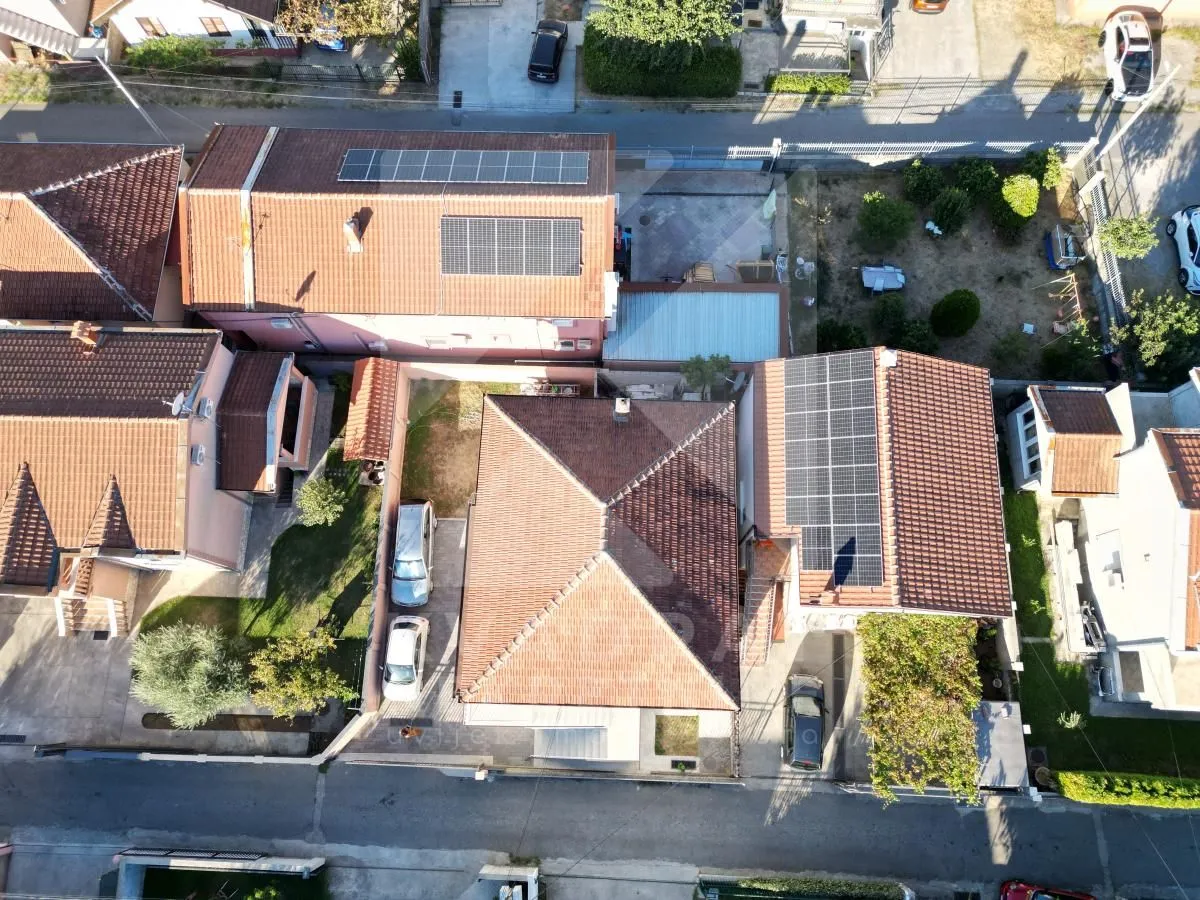 Pogled iz vazduha na kuće i dvorišta sa solarnim panelima na krovu.