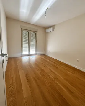 Empty room with wooden flooring, air conditioning unit, and balcony doors. - image 10
