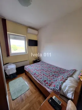 Nameštena spavaća soba sa krevetom, prozorom i televizorom na zidu. - image 4