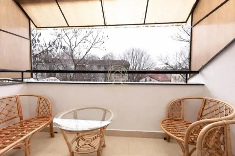 Natkriveni balkon sa pletenim nameštajem i pogledom na naselje. - image 14