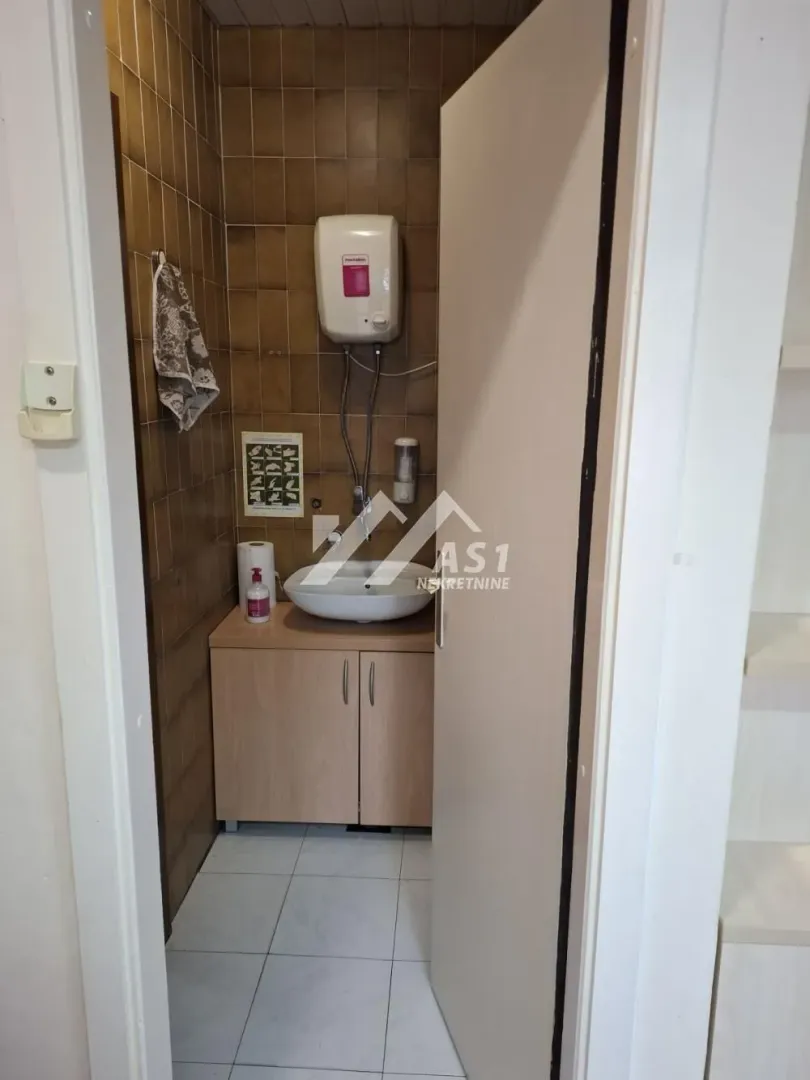 View of the bathroom with a sink, cabinet, and water heater.